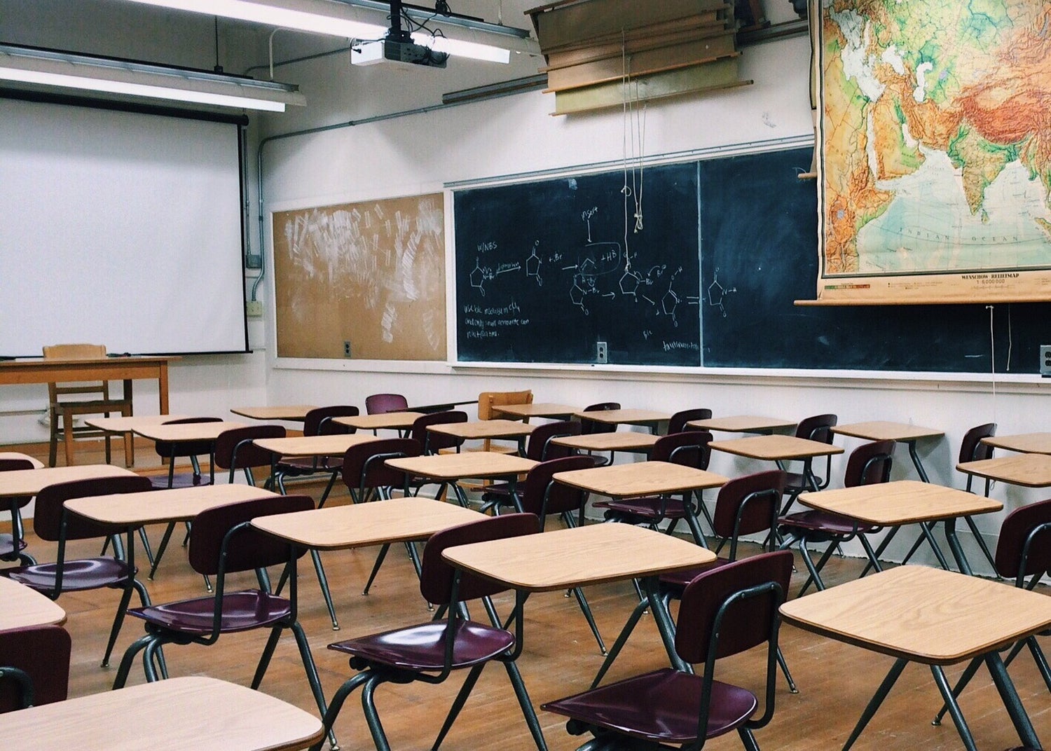 classroom with desk and blackboards and pull down map