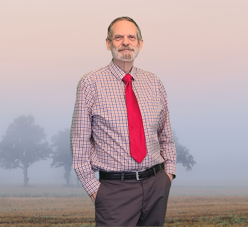 Hypnotist Bill Torgan standing alone in a field with trees in the background.